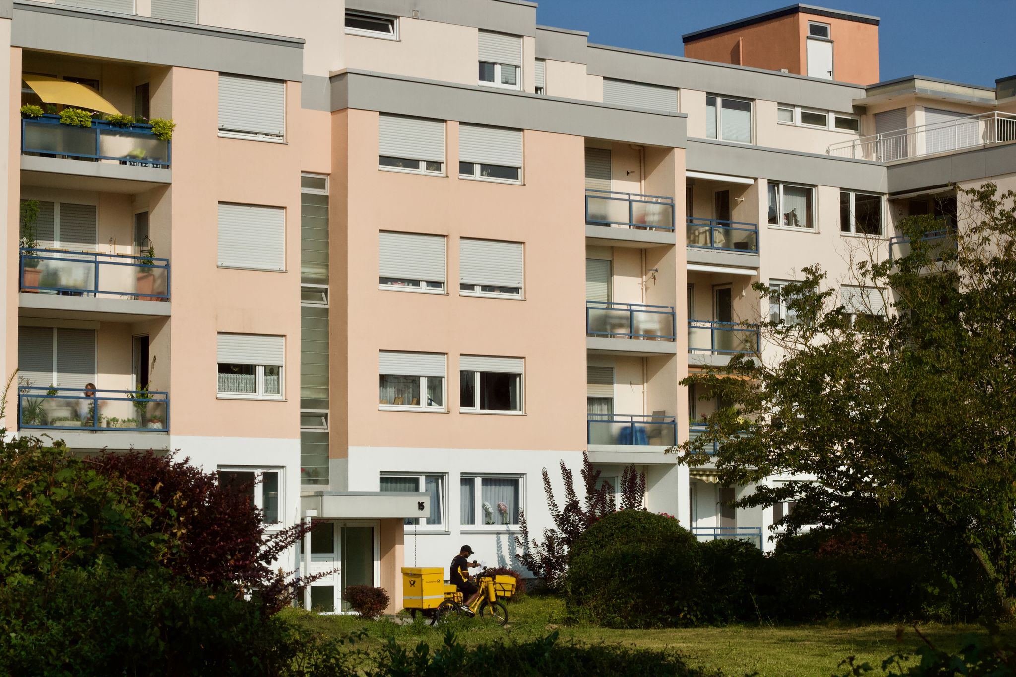 Residential building with a delivery scooter in a sunny urban setting, highlighting urban life.