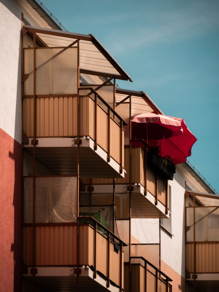 A detailed view of modern apartment balconies featuring vibrant colors and structures on a sunny day.