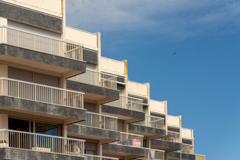 A modern apartment building with distinct balconies against a clear blue sky.